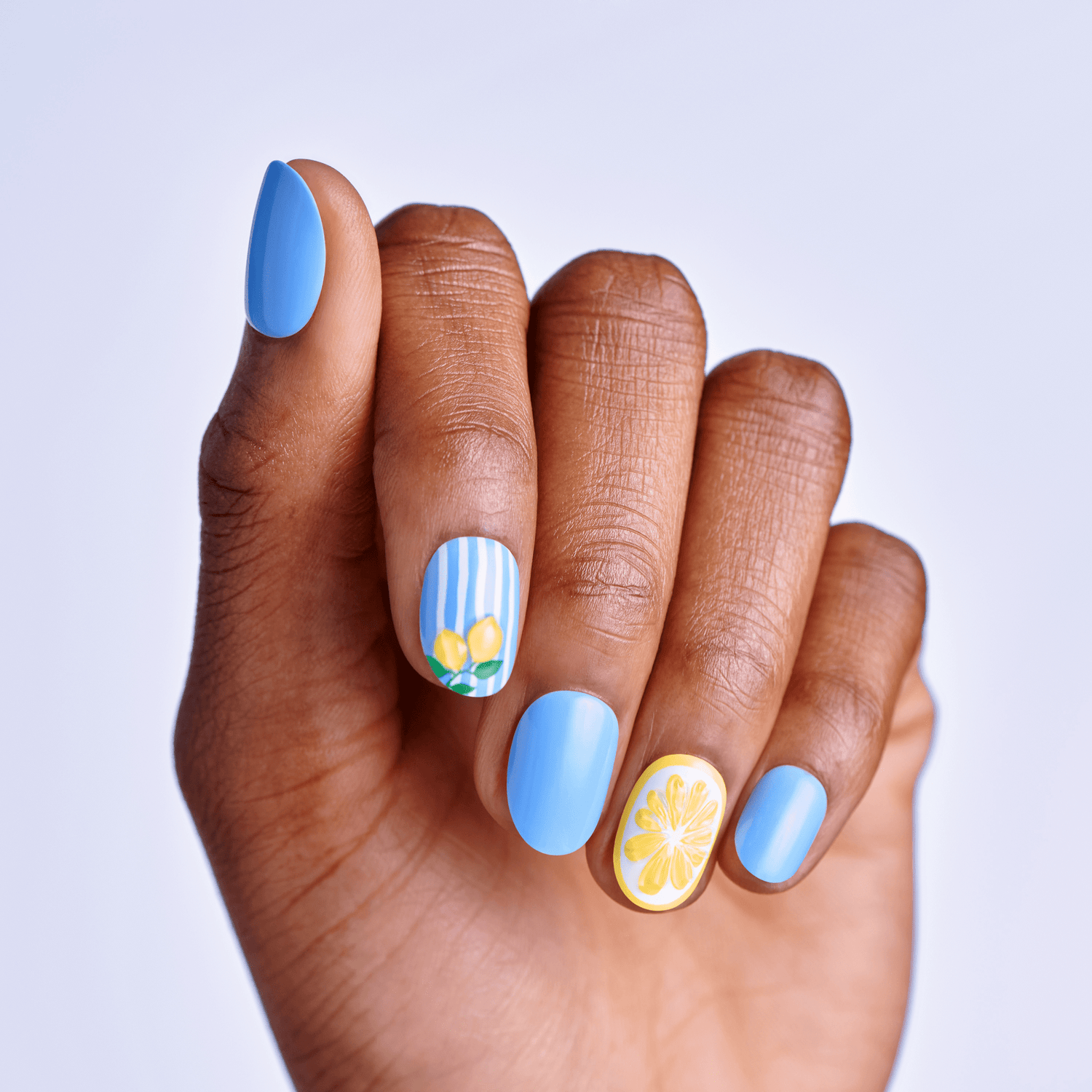 Hand with blue nail polish and floral designs on a light gray background