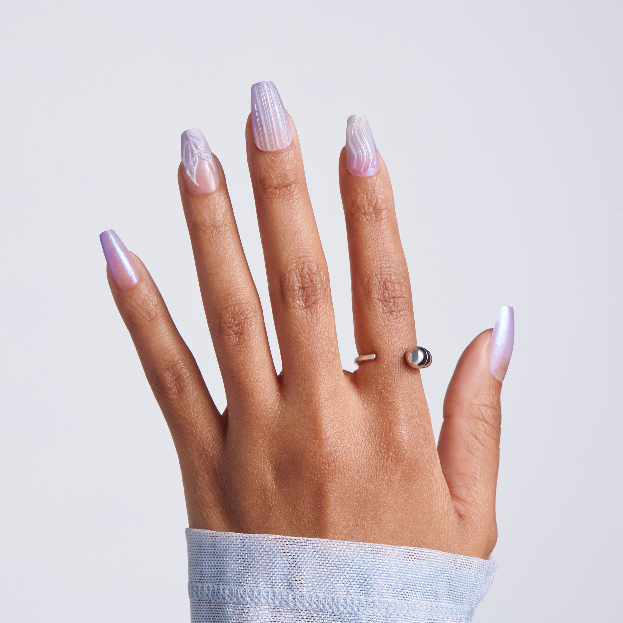 Hand with pastel nail polish and a ring on a light gray background