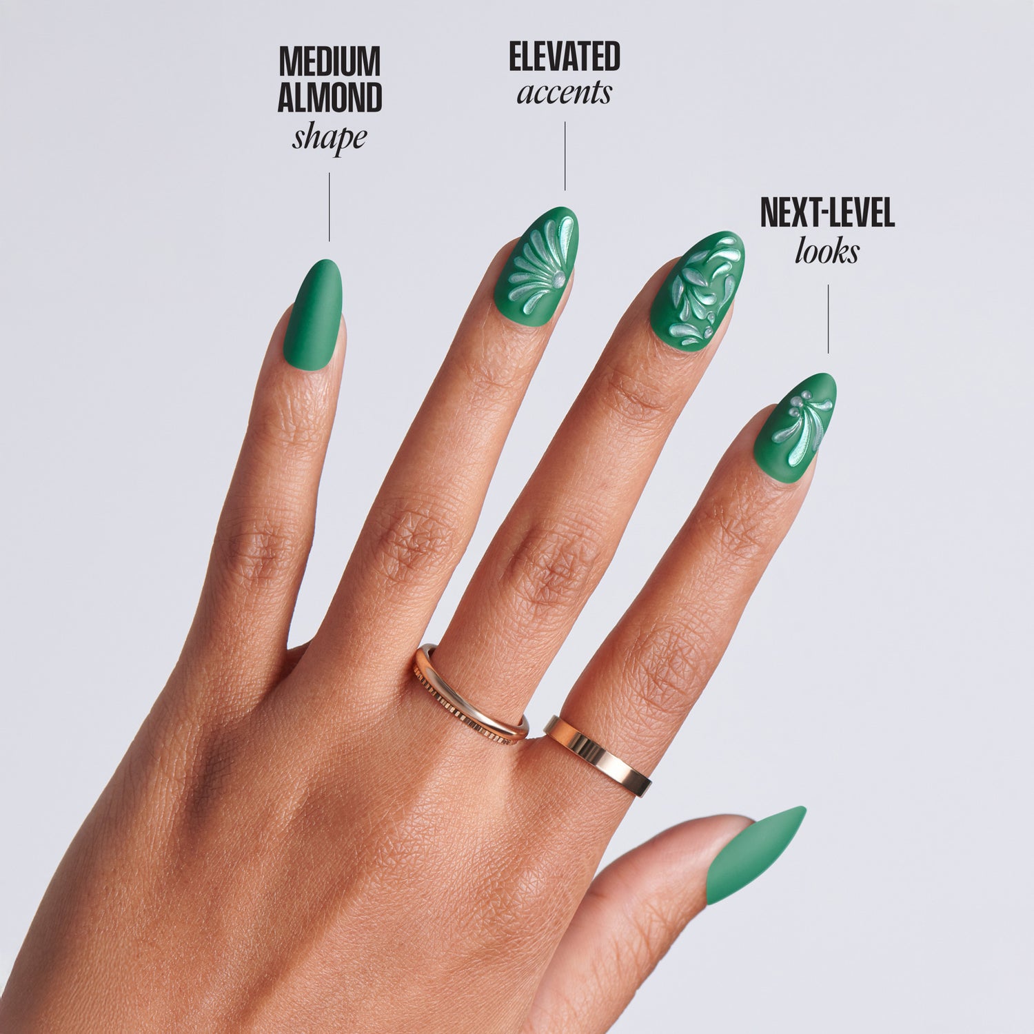 Hand with medium almond-shaped dark green press-on nails featuring white embossed floral nail art and gold ring, with text: Medium Almond Shape, Elevated Accents, Next-Level Looks