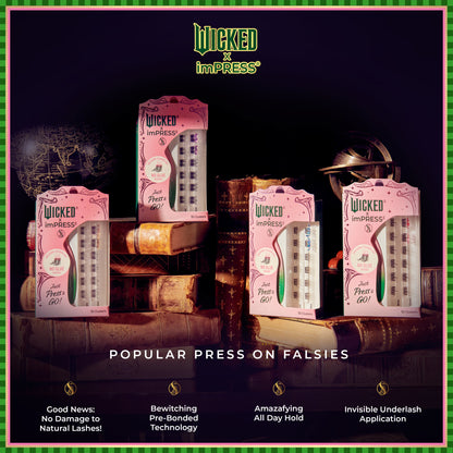 Four pink-packaged Wicked x imPRESS press-on falsies displayed on stacked vintage books with a dark background.