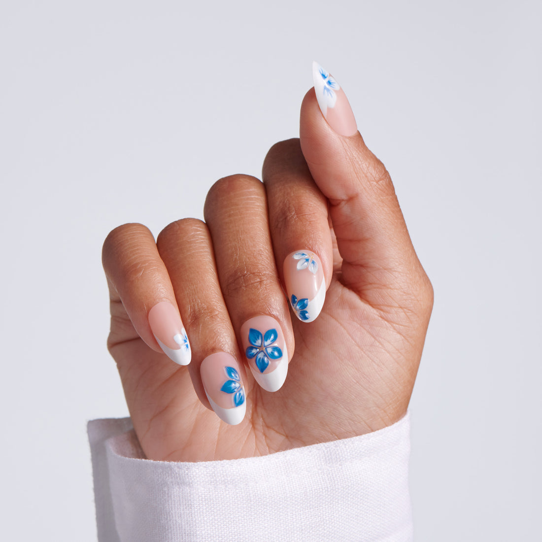 Hand with blue floral nail design on a light gray background