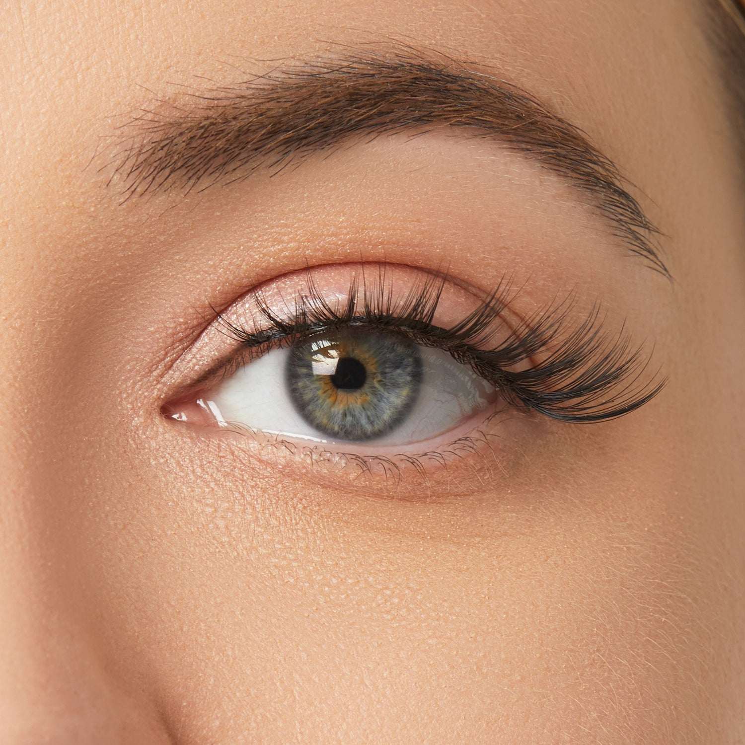 Close-up of eye with winged eyeliner, dark eyebrow, and false lashes on fair skin.