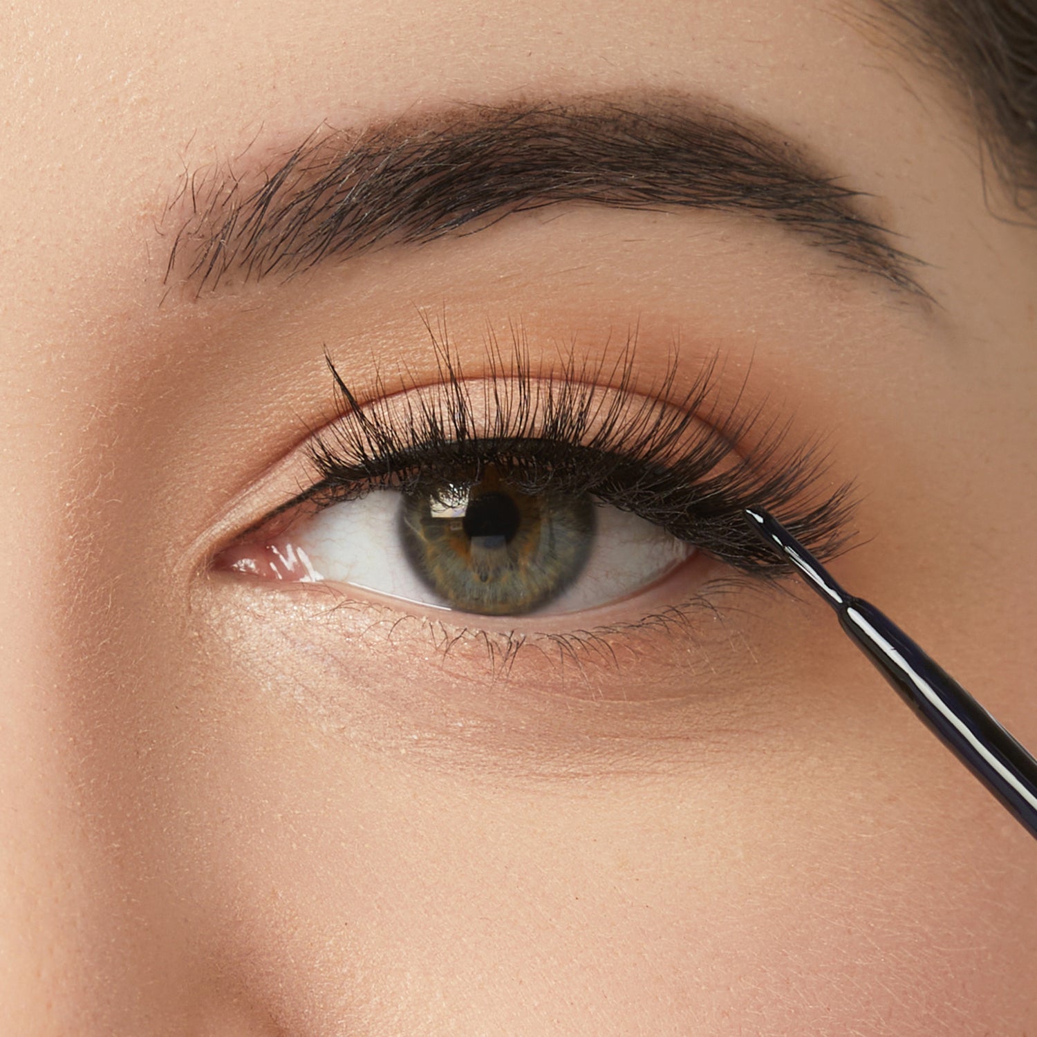 Close-up of eye makeup application with eyeliner brush and natural eyeshadow look
