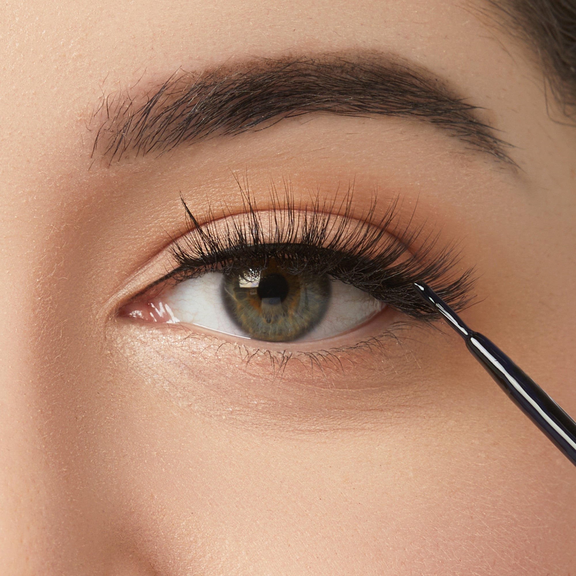 Close-up of eye makeup application with eyeliner brush and natural eyeshadow look