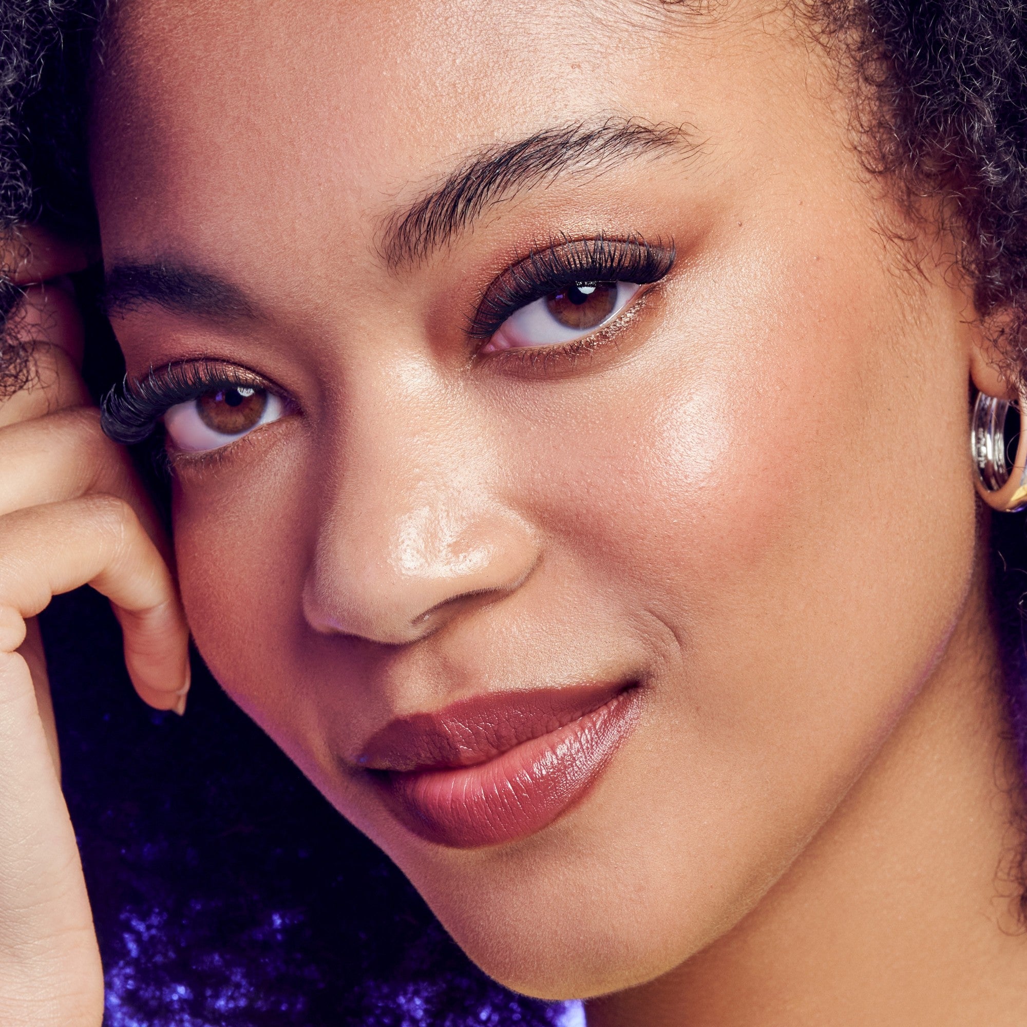 Close-up of a woman with a soft smile, wearing earrings.