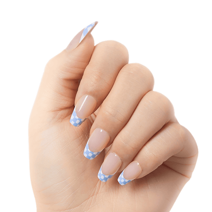 Close-up of a hand modeling medium, coffin shaped nails in French nail design with blue and white checker print. Nails are &