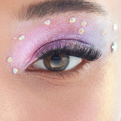 Close-up of an eye with pink glittery makeup and rhinestone accents.
