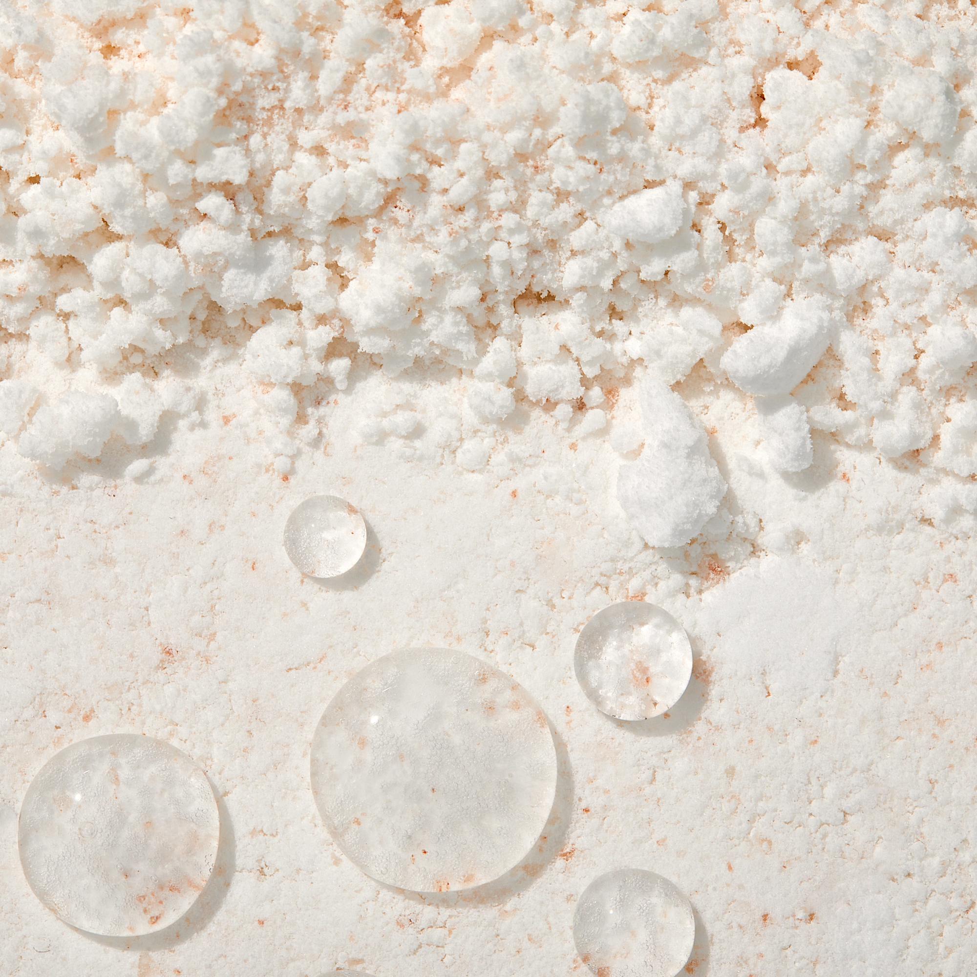 Close-up of white salt crystals with water droplets on a textured surface
